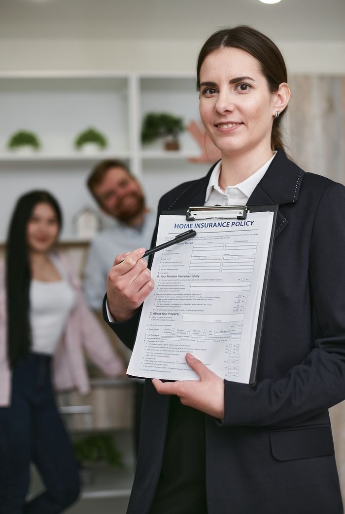 team-02 Confident businesswoman presenting a home insurance policy indoors to potential clients.